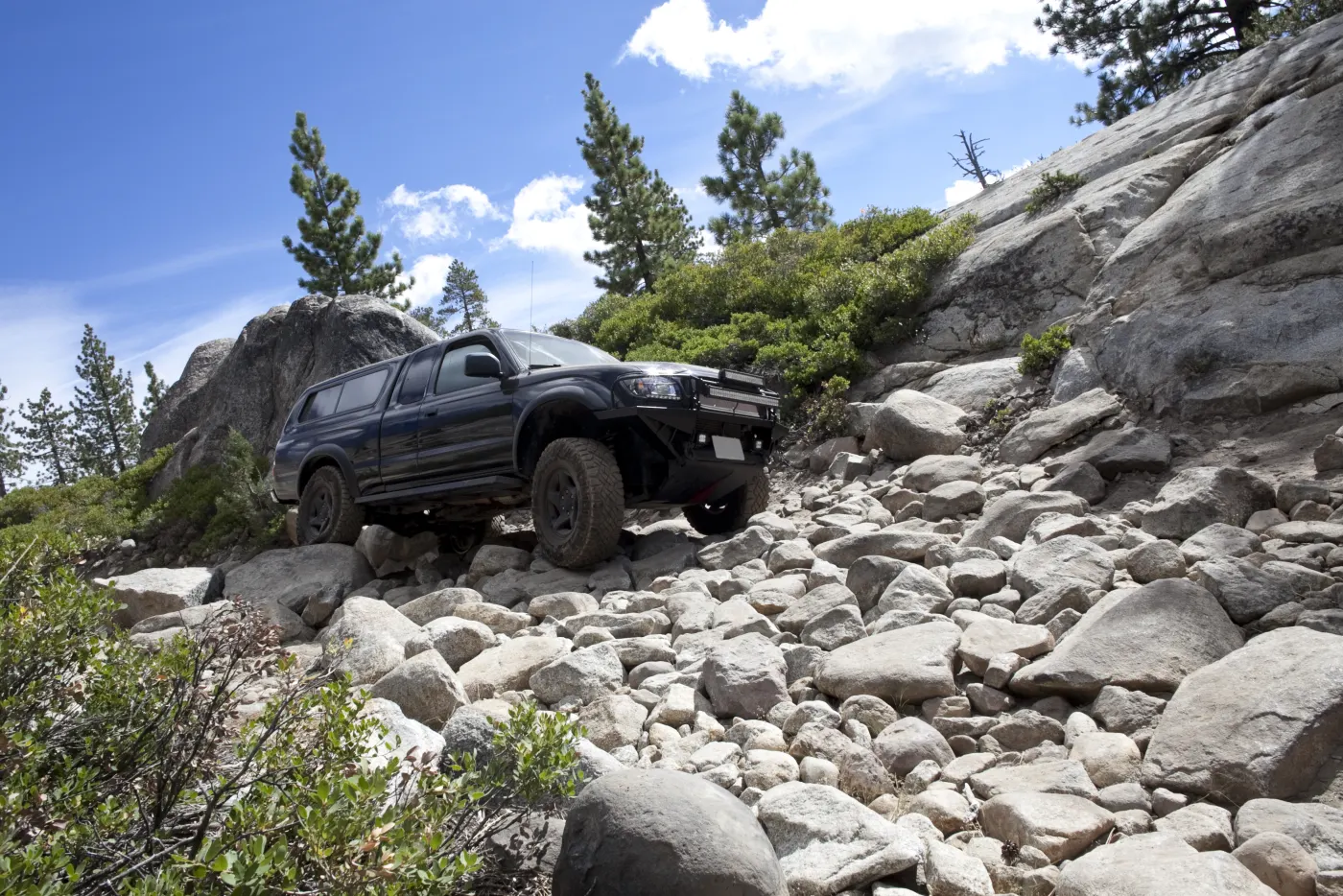 Four-wheel drive pickup climbing a rocky mountain trail