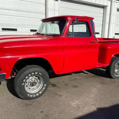 Red 1960s Chevrolet pickup outside the shop's roll-up doors