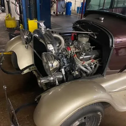 Chrome engine bay of a hot rod on the lift inside the shop