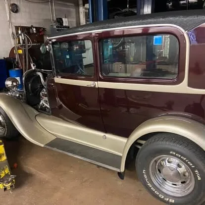 Two-tone maroon hot rod sedan parked in a service bay